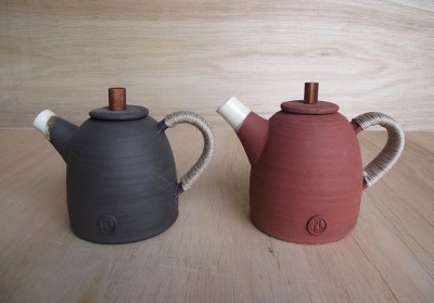 Stoneware medium sized teapots glazed on the inside the outside colour is the clay body. Copper lid top and fine hemp sail makers thread on the handle.